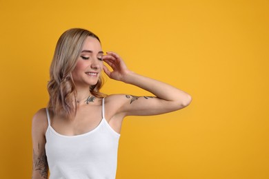 Beautiful woman with tattoos on body against yellow background