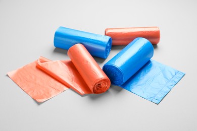 Rolls of different color garbage bags on light background