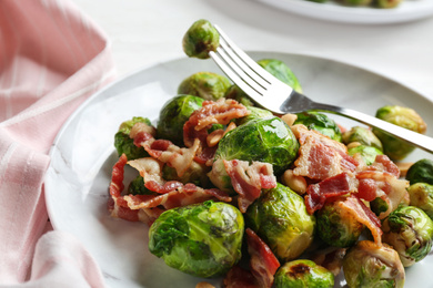 Delicious Brussels sprouts with bacon on table, closeup