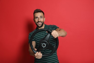 Happy man with steering wheel on red background