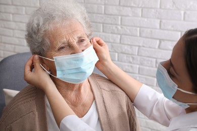Photo of Doctor putting protective mask on senior woman at nursing home