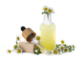 Bottle of chamomile essential oil and flowers on white background