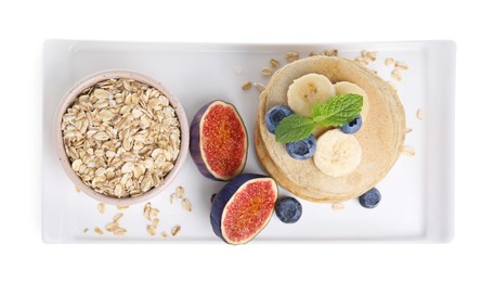 Tasty oatmeal pancakes and ingredients on white background, top view
