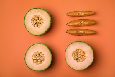Cut different types of melons on orange background, flat lay
