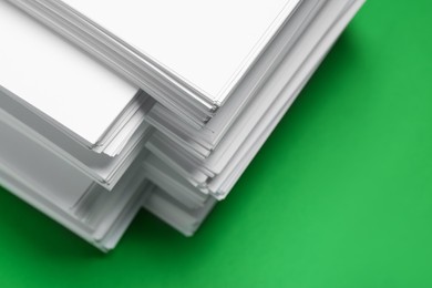 Photo of Stack of white paper on green background, closeup. Space copy text
