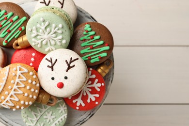 Beautifully decorated Christmas macarons on white wooden table, top view. Space for text