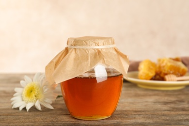 Jar with sweet honey on table against color background