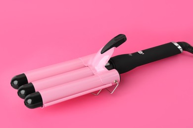 Modern triple curling iron on pink background