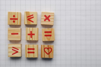 Photo of Wooden cubes with mathematical symbols and heart on sheet of grid paper, flat lay. Space for text