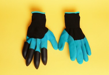 Photo of Gardening gloves on yellow background, above view