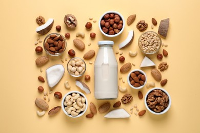 Vegan milk and different nuts on beige background, flat lay