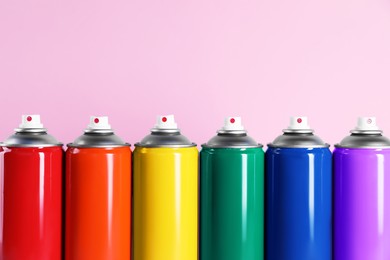 Colorful cans of spray paints on pink background