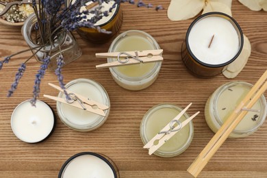 Glass jars with wax on wooden table, flat lay. Handmade candles