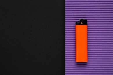 Photo of Stylish small pocket lighter and purple corrugated fiberboard on black background, top view. Space for text