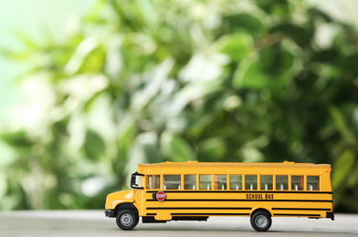Yellow school bus on table against blurred background. Transport service