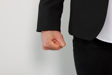 Young man showing fist on white background, closeup. Aggression concept