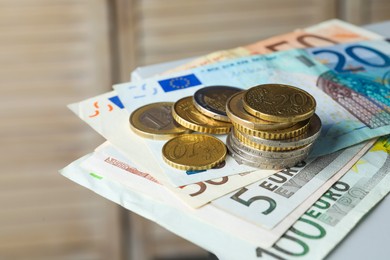 Euro banknotes and coins on blurred background, closeup