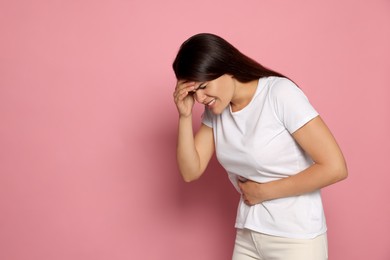 Young woman suffering from menstrual pain on pink background, space for text