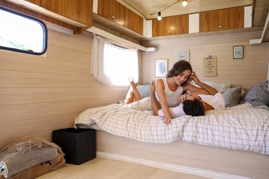 Happy young couple on bed in trailer. Camping vacation