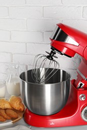 Photo of Modern red stand mixer, croissant and cookies on white wooden table