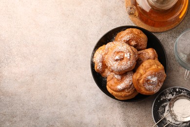 Photo of Delicious profiteroles with powdered sugar and tea on grey table, flat lay. Space for text