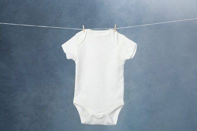 Child's bodysuit hanging on laundry line against dark background