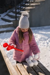 Cute little girl playing with snowball maker outdoors