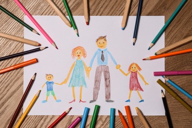 Family drawing and colorful pencils on wooden table, flat lay
