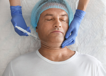 Mature man with double chin receiving injection in clinic, above view