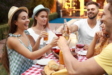 Photo of Happy friends with drinks having fun at barbecue party outdoors