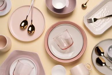 Different dishware and cutlery on beige background, flat lay