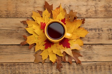 Cup of hot tea and autumn leaves on wooden table, flat lay