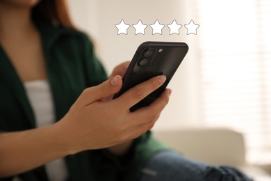 Woman leaving review online via smartphone, closeup. Five stars over gadget