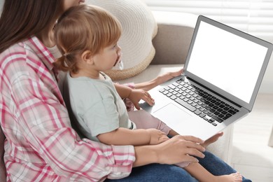 Mother and daughter with laptop on sofa at home. Pediatrician online consultation