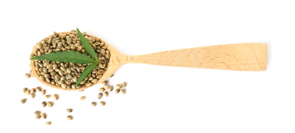 Spoon with hemp seeds and green leaf on white background, top view