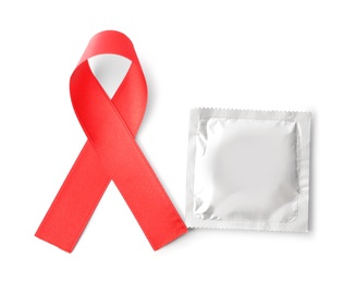 Red ribbon and condom isolated on white, top view. AIDS disease awareness