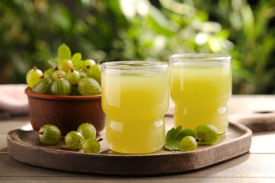 Photo of Tasty gooseberry juice and fresh berries on wooden table
