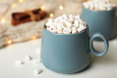 Delicious cocoa drink with marshmallows on white table