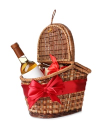 Festive basket with bottle of wine and gift on white background