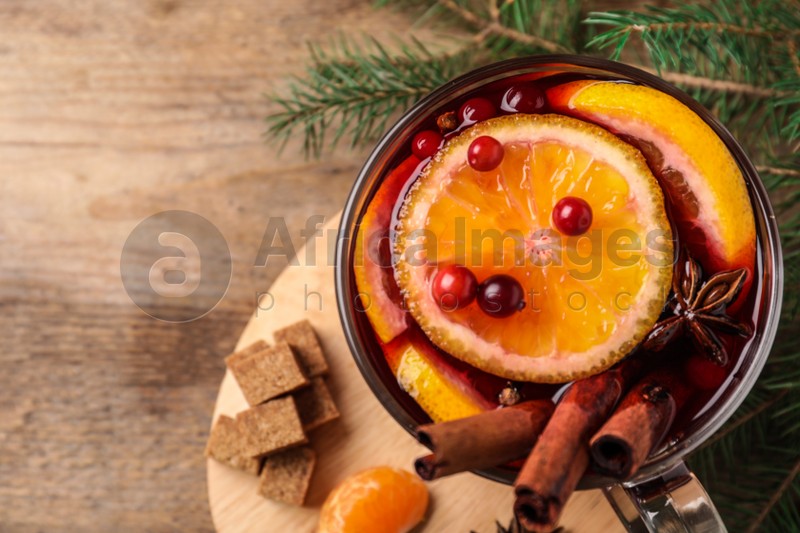 Glass cup of tasty mulled wine on wooden table, flat lay