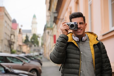Tourist with camera taking photos on city street