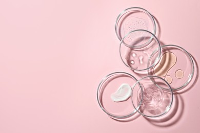 Many Petri dishes with cosmetic samples on pink background, flat lay. Space for text