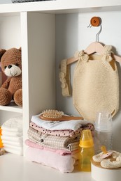 Baby clothes, toy and accessories on white rack
