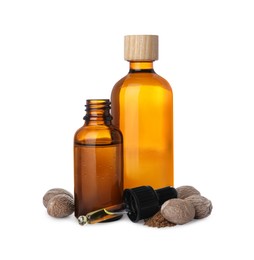 Bottles of nutmeg oil, nuts and pipette on white background
