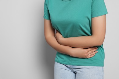 Photo of Young woman suffering from menstrual pain on grey background, closeup