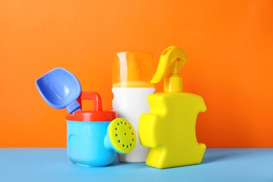 Photo of Different suntan products and plastic beach toys on color background