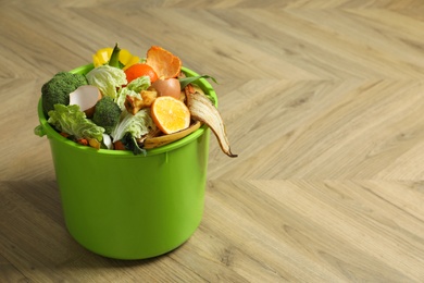 Trash bin with natural garbage on wooden background, space for text. Composting of organic waste