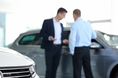 Blurred view of car dealership with salesman and client