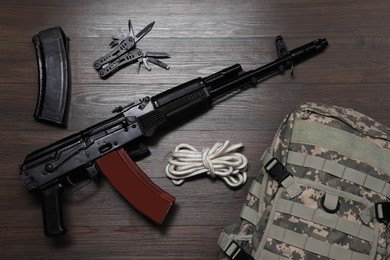 Flat lay composition with gun and military knapsack on wooden table