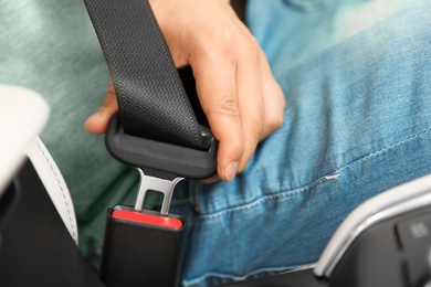 Photo of Male driver fastening safety belt in car, closeup